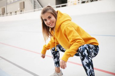 Alıştırma yapmadan önce kaslarını ısıtıp gülümseyen çekici bir kadın. Yaşam tarzı olarak spor ve spor. Atletik açık hava.