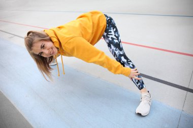 Alıştırma yapmadan önce kaslarını ısıtıp gülümseyen çekici bir kadın. Yaşam tarzı olarak spor ve spor. Atletik açık hava.