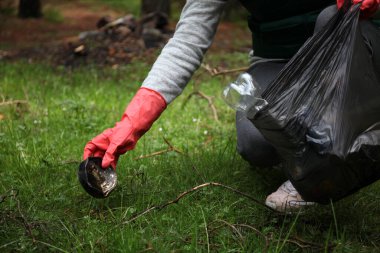 Eldivenle çöpleri temizler ve ormanda atıkları temizler. Yeşil gönüllü. Çevre bakımı.