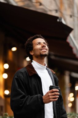 Çekici bir Afrikalı adamın açık havada bir fincan kahveyle portresi..