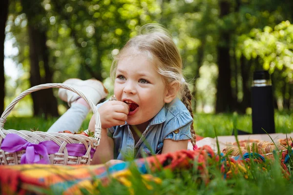 Wesoła Dziewczynka Jedząca Truskawki Pikniku Parku Siedząca Zielonej Trawie Uśmiechnięta — Zdjęcie stockowe