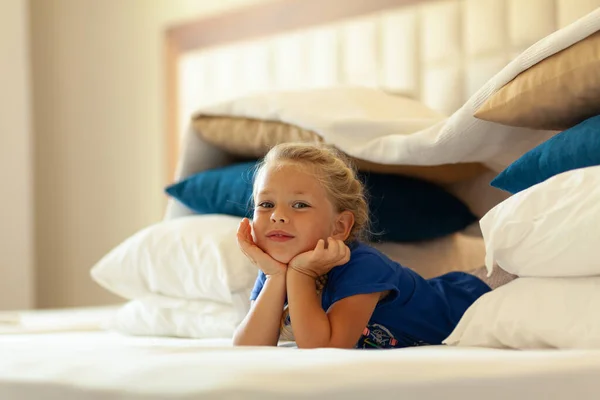 Küçük tatlı kız yastık ve battaniyelerden (kale, ev) doğaçlama kaleler inşa etti. El yapımı çadır kulübesi.