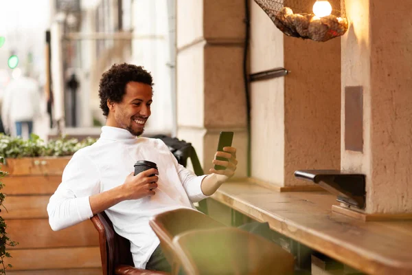 Een Jonge Aantrekkelijke Afrikaanse Man Glimlacht Kijkt Naar Telefoon Stad — Stockfoto