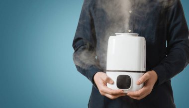 Erkeklerin elinde buharla çalışan bir nemlendirici. Evde temiz hava kavramı..