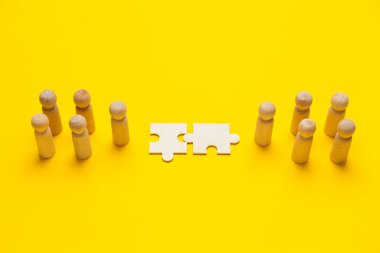 Sarı arka planda pazzleri olan ahşap figürler. İş adamları arasındaki anlaşma, işbirliği ve anlaşma konsepti. Başarılı bir sözleşme.. 