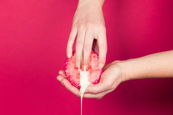 Seksten önce mastürbasyon ve ön sevişme (ön sevişme) sembolü olarak kırmızı arka planda bir kadın eli ve bir çörek. Klitorise dokun, erotik konsept..