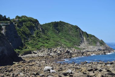 Bir uçurumun tepesinde beyaz ve mavi deniz feneri.