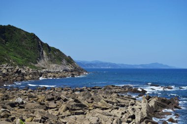 Bir uçurumun tepesinde beyaz ve mavi deniz feneri.