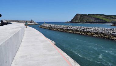 Bir tahta kaldırımdan kayalıklarla sahil manzarası.