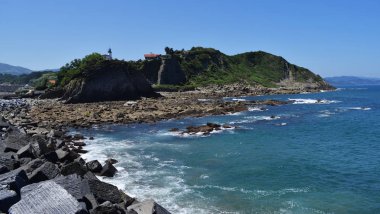 Bir uçurumun tepesinde beyaz ve mavi deniz feneri.