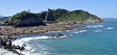 Bir uçurumun tepesinde beyaz ve mavi deniz feneri.