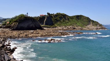 Bir uçurumun tepesinde beyaz ve mavi deniz feneri.