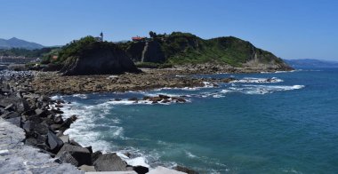 Bir tahta kaldırımdan kayalıklarla sahil manzarası.