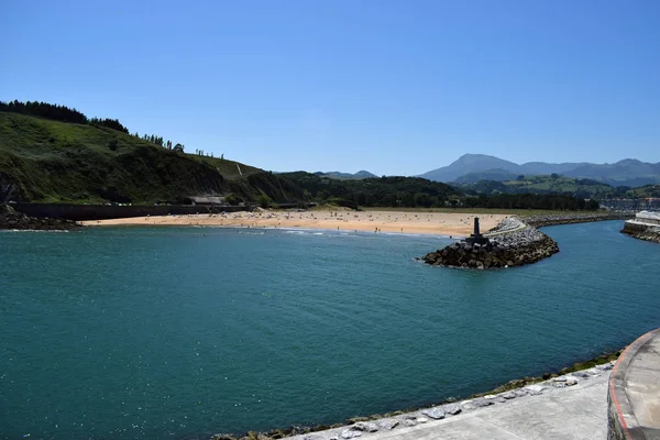 Entry and exit of a river to the sea, next to a beach.