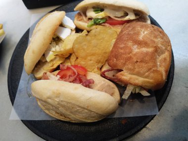 Siyah tabakta iki et li sebzeli sandviç.