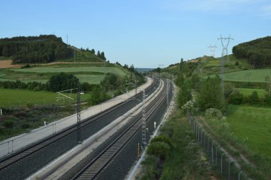 Bir bahar manzarası boyunca giden tren rayları.