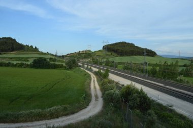 Bir bahar manzarası boyunca giden tren rayları.