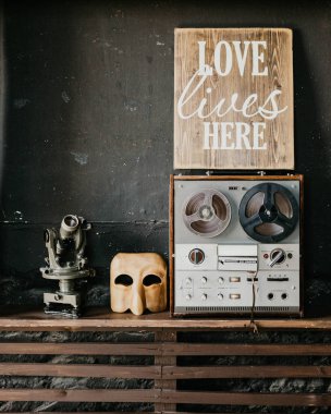 Bir çatı iç ahşap bir rafta duran Vintage nesneler: retro teyp, mikroskop ve ahşap maske 