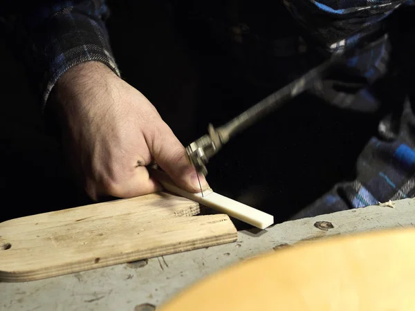 Gitaren Luthiers snijdt een deel van de moer. — Stockfoto