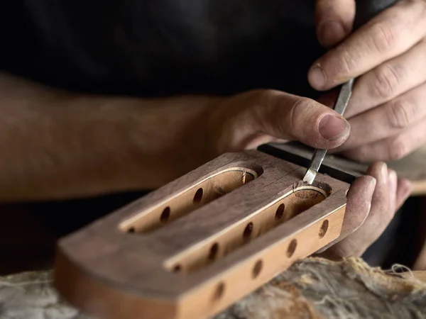 luthier modifies the head of classical guitar.