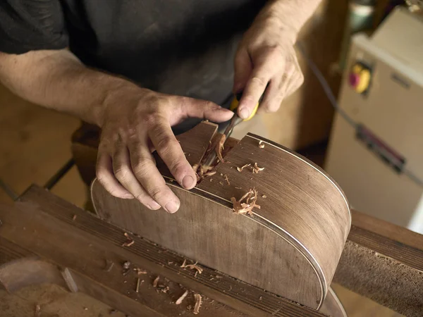 Luthier makes a neck block on classical guitar.