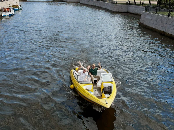 Ein gelbes lustboot schippert auf den kanälen der stadt st. petersburg, russland. Ein junges Paar ist auf einem Schnellboot unterwegs. — Stockfoto