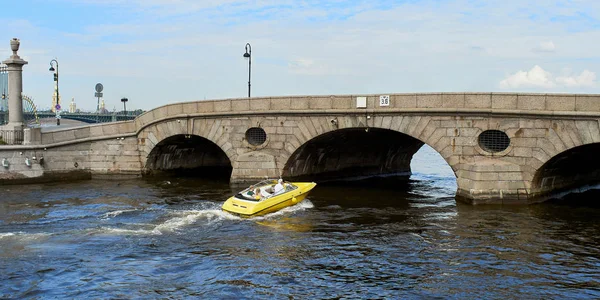 Un bateau de plaisance jaune navigue le long des canaux de la ville de Saint-Pétersbourg, Russie. Un jeune couple voyage en hors-bord . — Photo