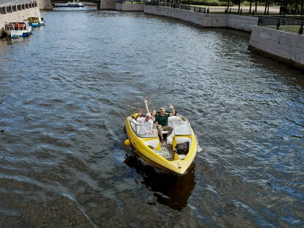 Ein gelbes lustboot schippert auf den kanälen der stadt st. petersburg, russland. Ein junges Paar ist auf einem Schnellboot unterwegs. — Stockfoto