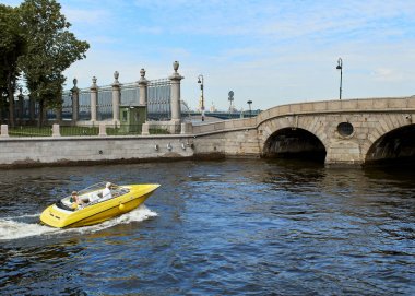 Sarı bir zevk teknesi St Petersburg, Rusya şehrinin kanalları boyunca yelken. Genç bir çift sürat teknesiyle seyahat ediyor..