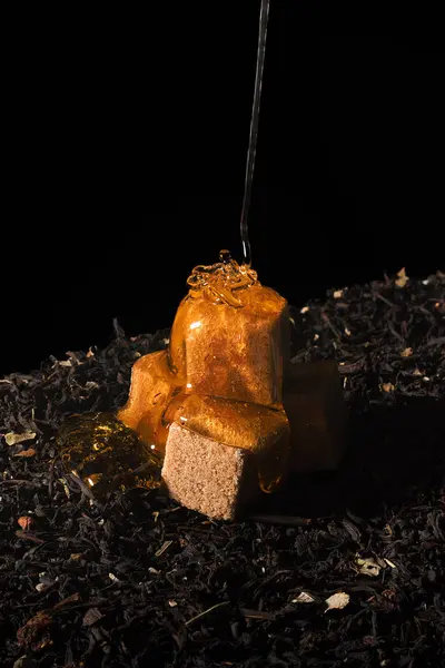 Мед льется на кубики сахара, которые стоят на чай . — стоковое фото