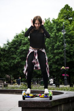 Kız hoverboard üzerinde parapet kenarında duruyor.