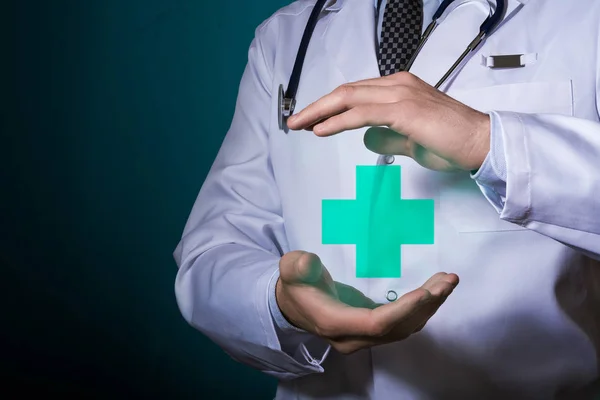 Az orvos piktogram a kezében a zöld kereszt. Az egészség szimbóluma. — Stock Fotó