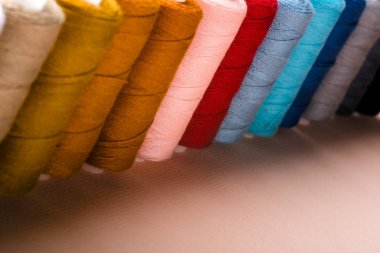 Pembe arka plan üzerinde çok renkli ipliklere sahip bobinler