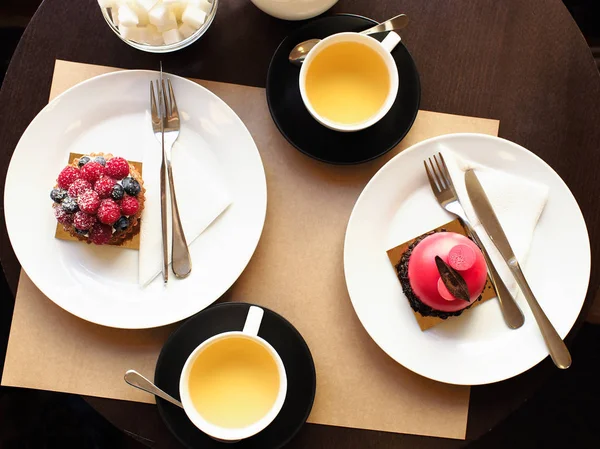 Малиновый и малиновый фисташковый торт с кружками чая на столе . — стоковое фото