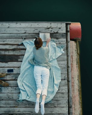 İskelede bir kitap okuma akşam için romantik ruh hali.