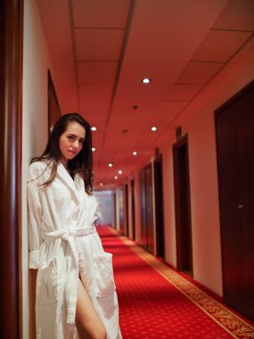 Esmer otelin koridorunda bir giyinme elbisesi içinde poz veriyor.