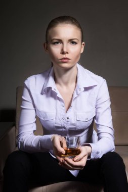 Güzel kız kanepede bir bardak viski ile oturuyor