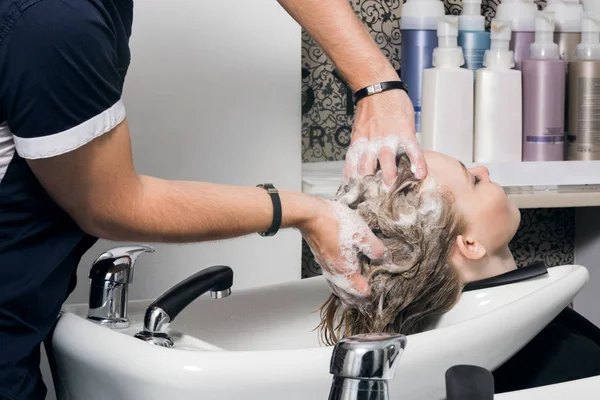 Young woman washing hair in salon.