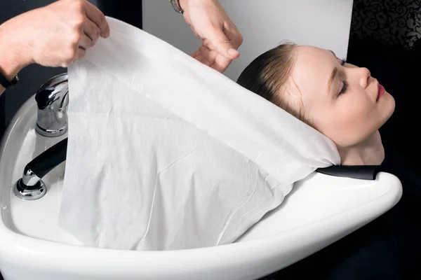 Genç bir kız başını yıkadıktan sonra havluya sarılır..