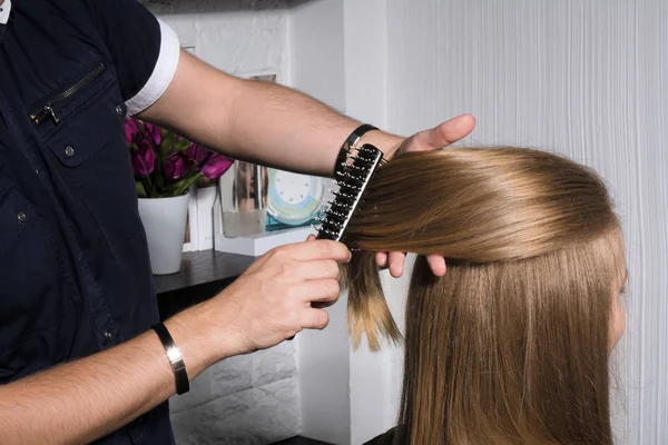 Mujer joven peinando el pelo en el salón . — Foto de Stock