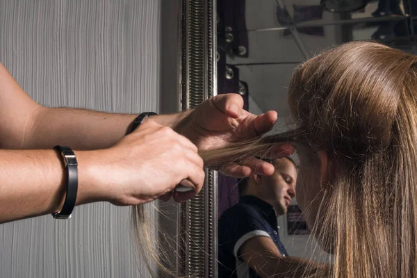 Парикмахер делает прическу молодой женщине в салоне . — стоковое фото