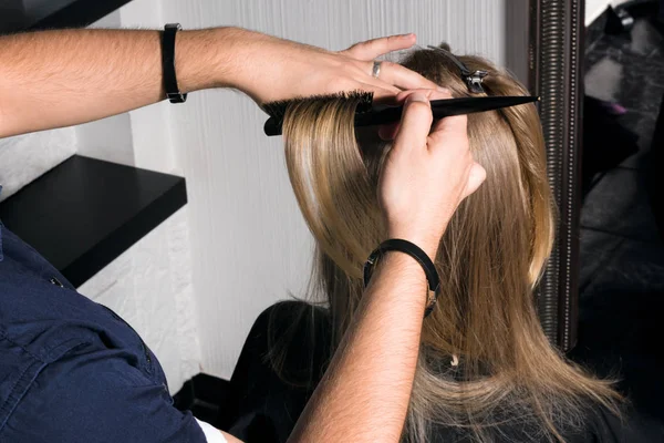 La peluquera hace el peinado a la mujer joven . — Foto de Stock