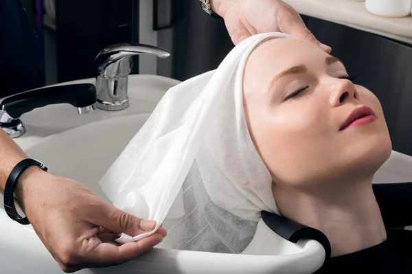 Genç bir kız başını yıkadıktan sonra havluya sarılır..