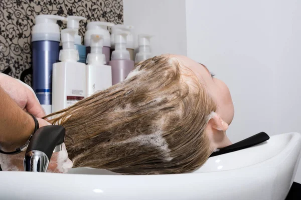 Молодая женщина моет волосы в салоне Стоковая Картинка