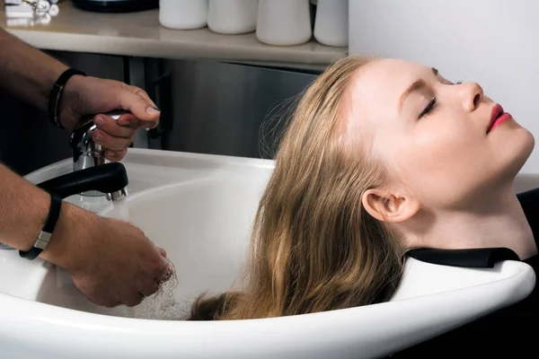Young woman washing hair in salon. Stock Photo