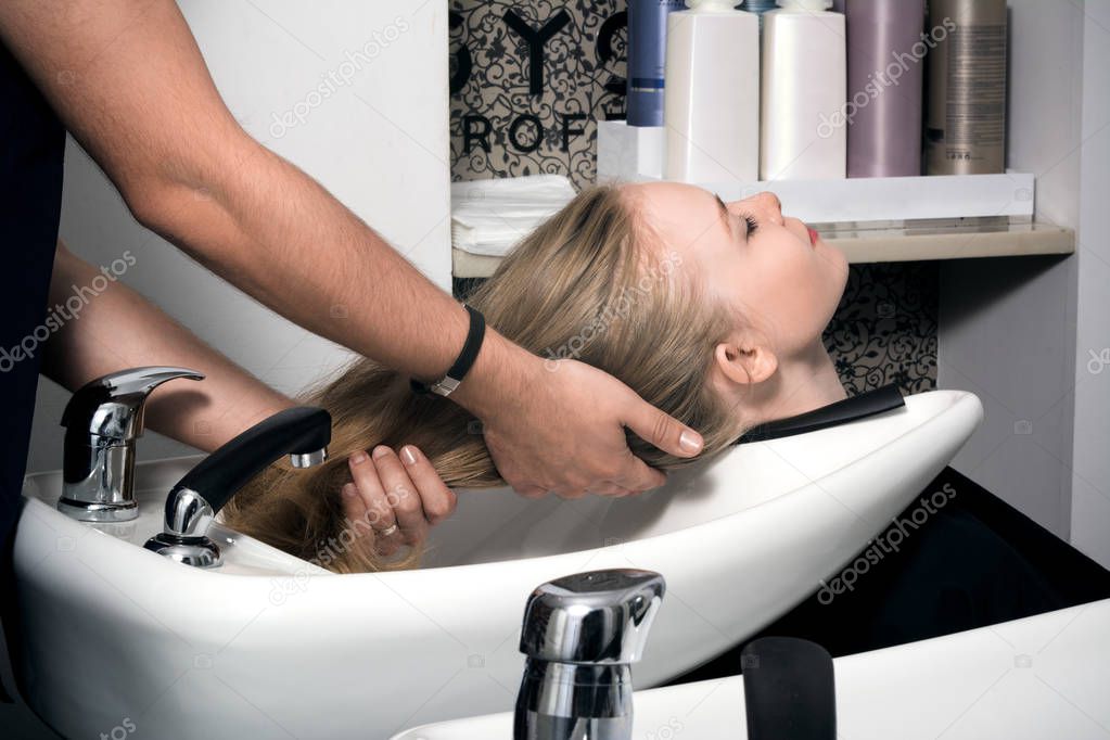 Young woman washing hair in salon. 