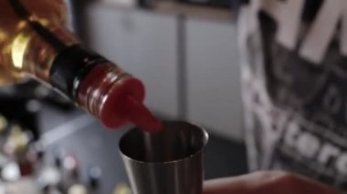 Barmen bir shaker içine alkol döker.