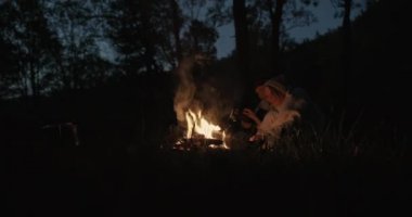 Genç bir çift ormanda geceleri oturur, bir şenlik ateşi önünde ortak bir ekose altında kucaklayan, konuşma ve gülerek.