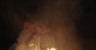 Genç bir çift ormanda geceleri oturur, bir şenlik ateşi önünde ortak bir ekose altında kucaklayan, konuşma ve gülerek.