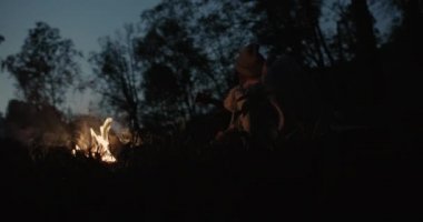 Genç bir çift ormanda geceleri oturur, bir şenlik ateşi önünde ortak bir ekose altında kucaklayan, konuşma ve gülerek.